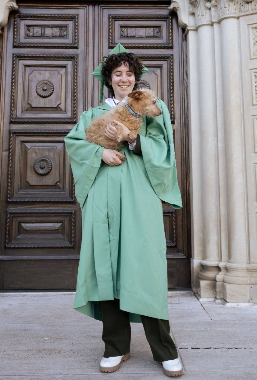 Ella Lehavi in graduation robes holding their childhood dog, Lilly